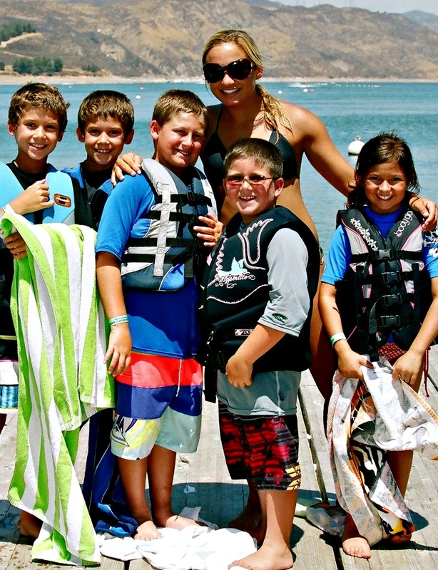 Four boys and one girl standing on the beach with their camp counselor in Hawaii.