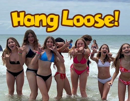 7 girls at summer camp in Hawaii giving the Hang Loose sign