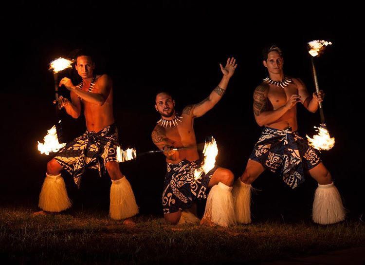 Three Hawaiian entertainers spinning fire sticks/torches at Aloha Beach Camp's summer camp luau in Oahu, Hawaii.