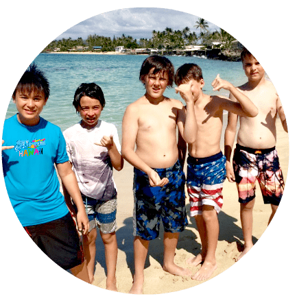 5 campers standing on the beach at Aloha Beach Camp's Hawaii summer camp program giving the 