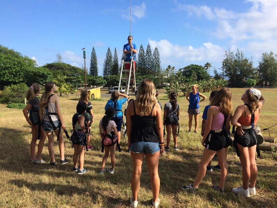 Campers receiving instruction from their Camp Counselor for how to safely participate on the Monster Alpine Tower and Giant Swing at Aloha Beach Camp's Hawaii summer camp program on the north Shore of Oahu.