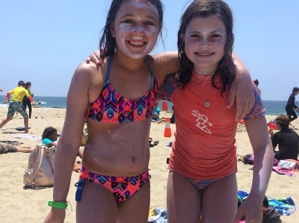 Two girls covered in sunscreen on the beach at Aloha Beach Camp's Hawaii summer camp.
