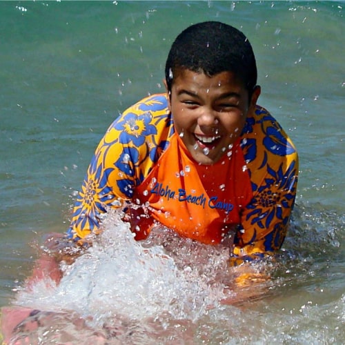 Happy boy boogie boarding at summer camp in Hawaii