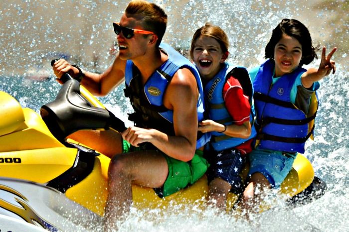 Two campers and their camp counselor jet skiing at summer camp in Hawaii.
