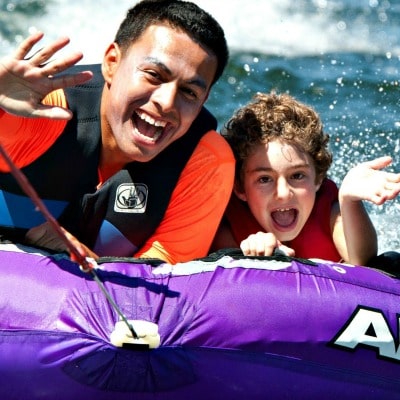 Camp counselor and camper riding an innertube together at Aloha Beach Camp's Hawaii summer camp on Oahu, Hawaii.
