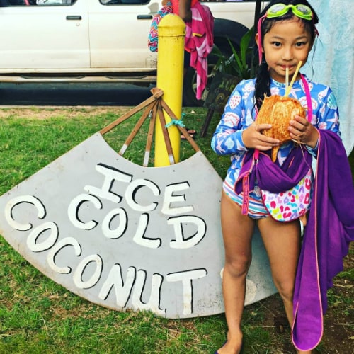 Young girl at summer camp in Hawaii enjoying a refreshing Ice Cold Coconut drink.