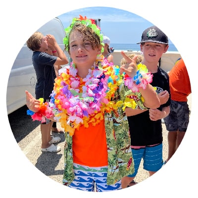 Boy wearing lots of flower leis at summer camp in Hawaii