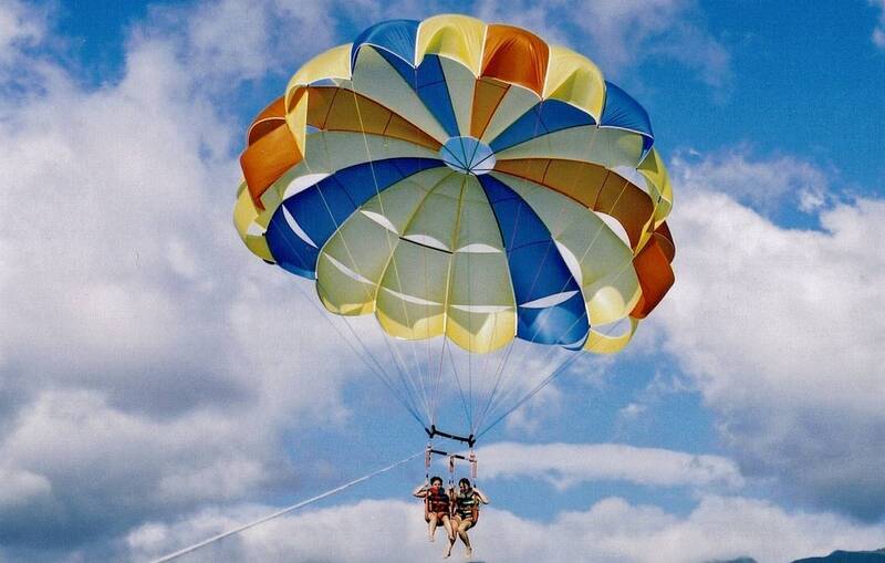 Two girls parasailing high above the Pacific Ocean at Aloha Beach Camp's Hawaii summer camp.