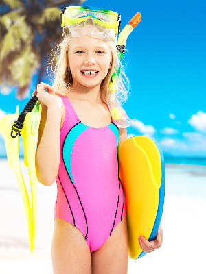 Summer camper girl holding a boogie board and snorkel at summer sleepaway camp in Hawaii