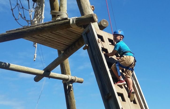 Boy climbing the large Alpine Tower at Aloha Beach Camp's Hawaii summer camp.